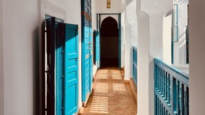 A corridor with blue doors and white walls, leading to a dark doorway. - Riad Khalifa (Marrakech)