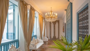 A corridor with ornate white furniture, a chandelier, and a view of the outside balcony. - Riad Khalifa (Marrakech)