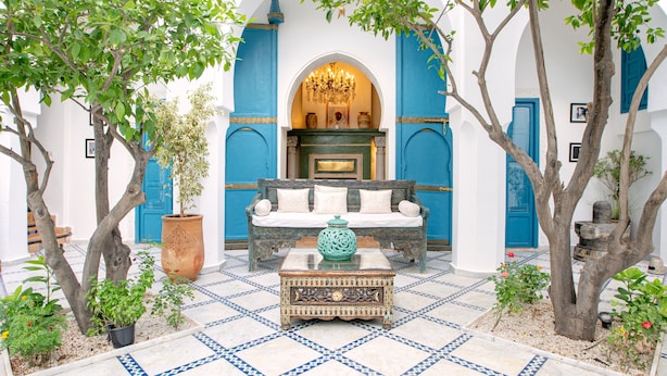 A courtyard with a blue sofa, a decorative coffee table, and potted plants. - Riad Khalifa (Marrakech)