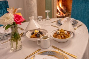 A dining table with two bowls of food, a vase with flowers, and a pitcher. - Riad Khalifa (Marrakech)