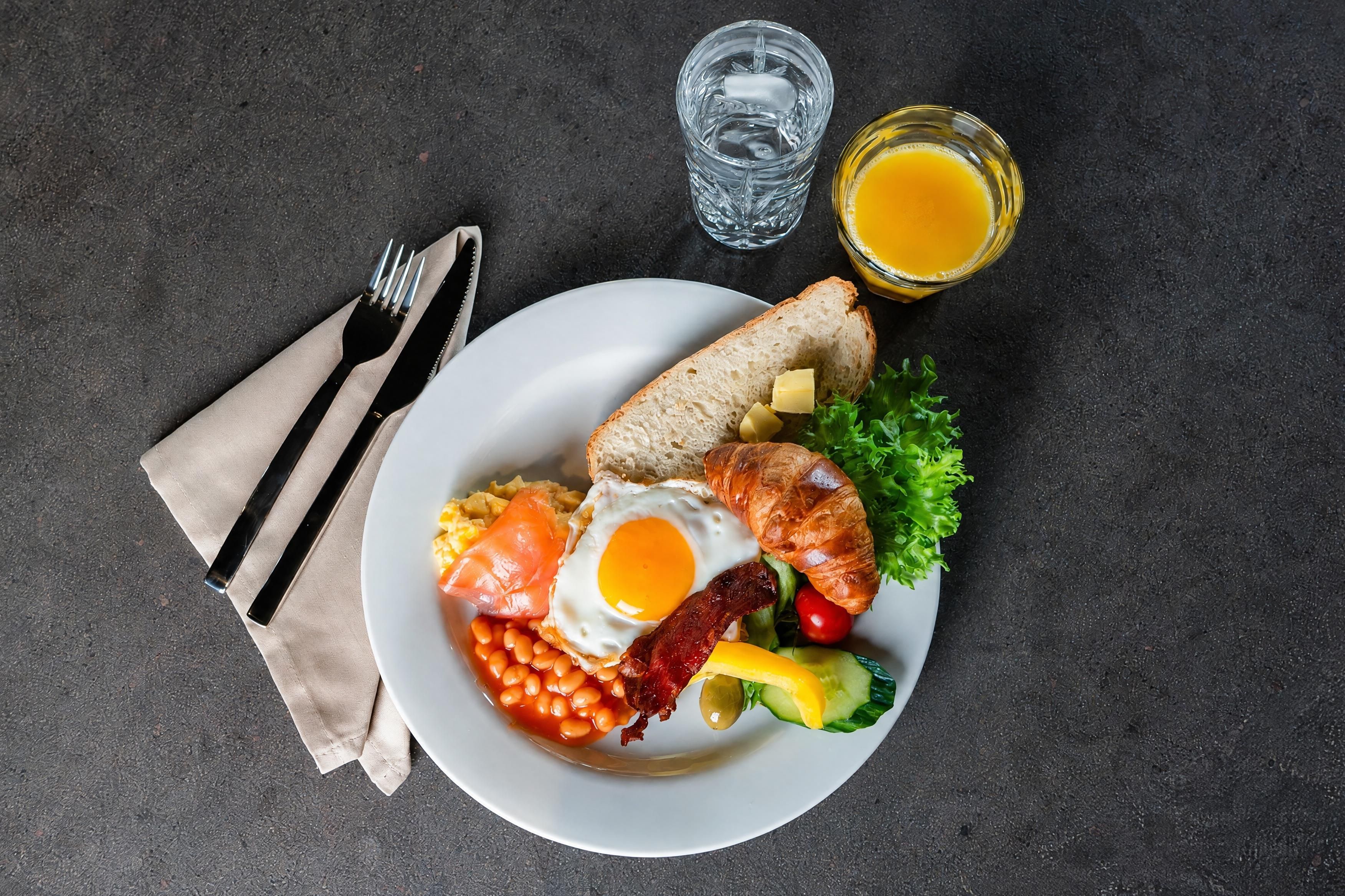Un plato de desayuno con huevos, tocino, tostadas y verduras.