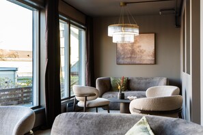 A modern living room with a sofa set, a round coffee table, and a chandelier. - Best Western Hotel Alta (Alta)