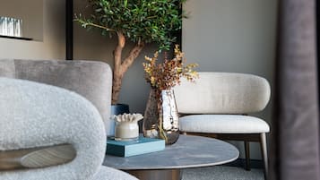 Una sala moderna con una mesa redonda, dos sofás grises, una planta en maceta y un jarrón decorativo.