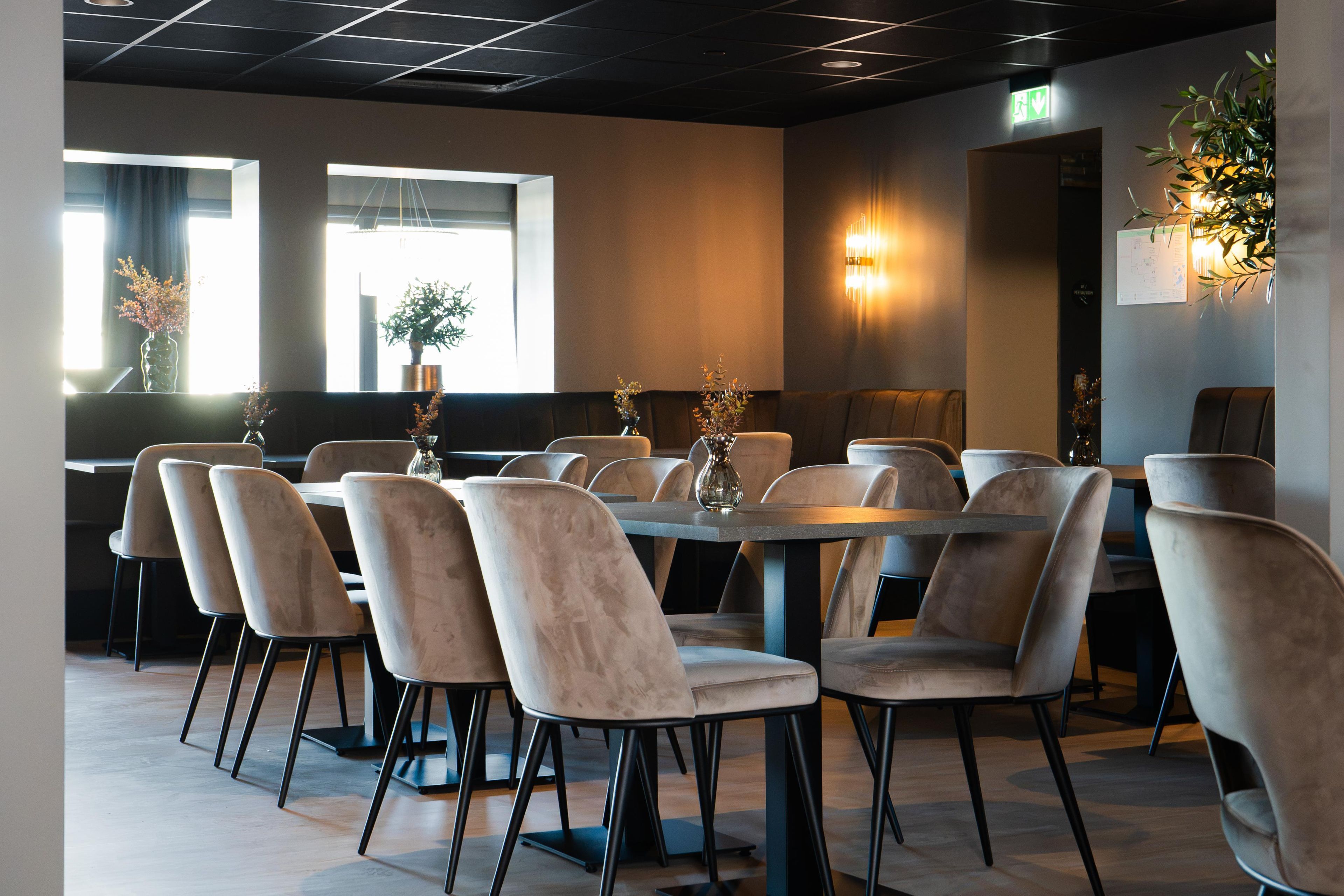 Ein Konferenzraum mit einem langen Tisch, mehreren Stühlen, großen Fenstern und Wandleuchten.