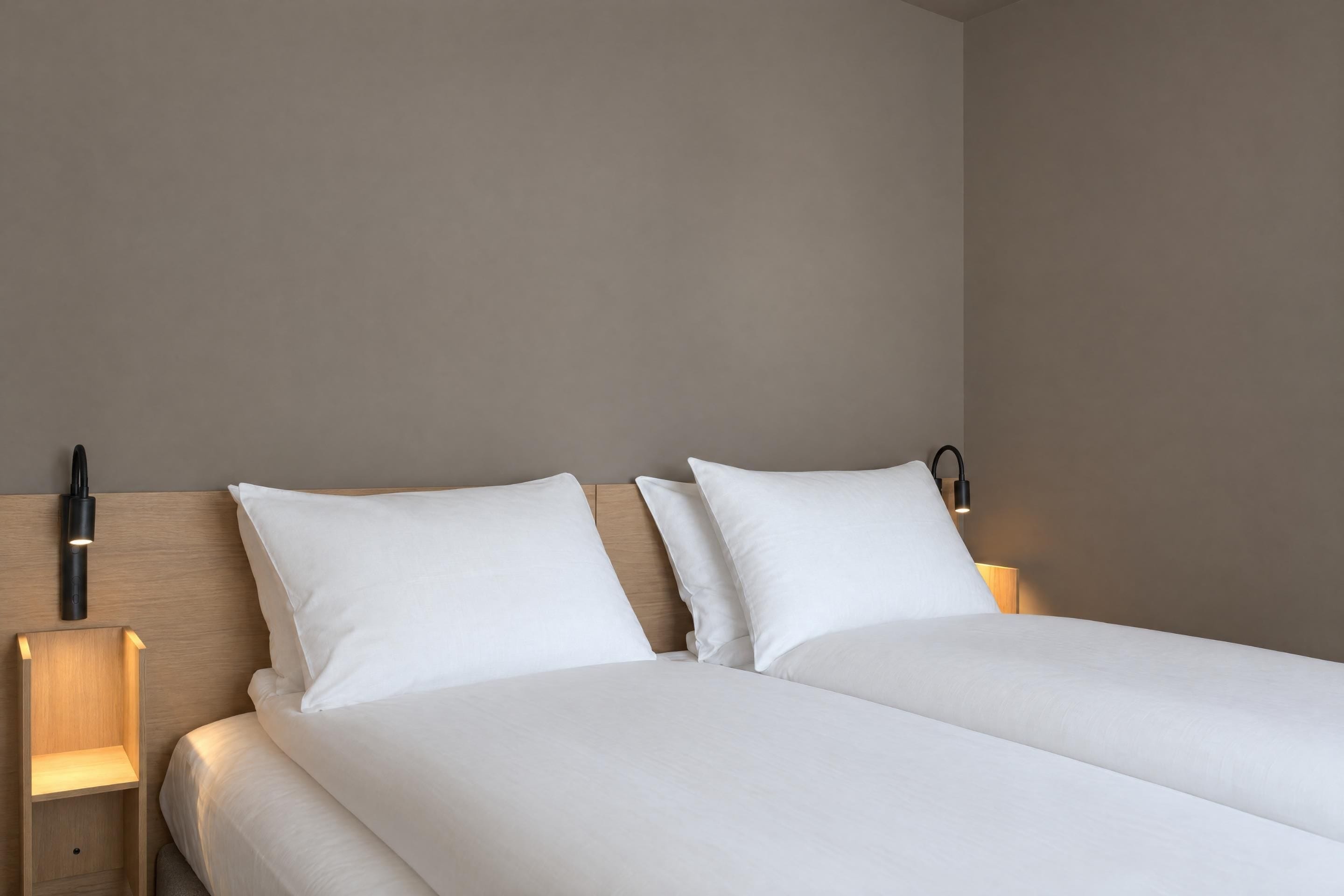 A double bed with white bedding, two bedside lamps, and a wooden headboard.