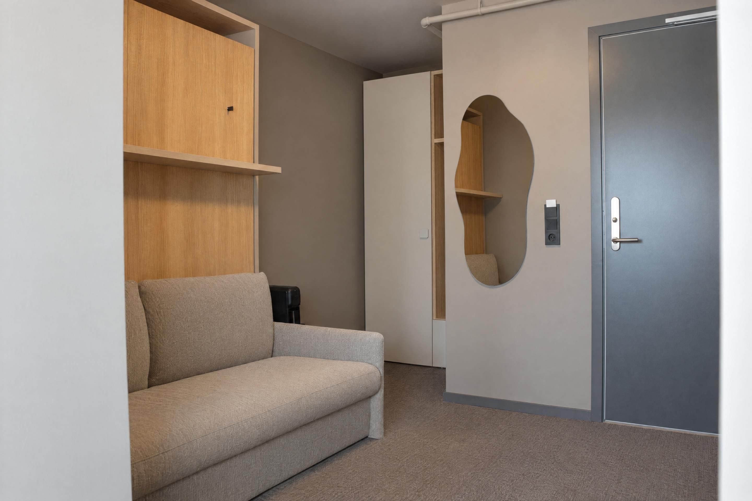 Een kamer met een bank, een deur en inbouwplanken.