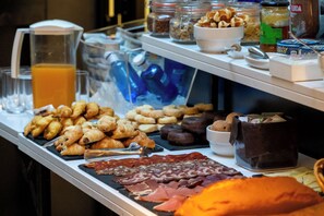 A buffet with various food items including pastries, meats, and condiments.