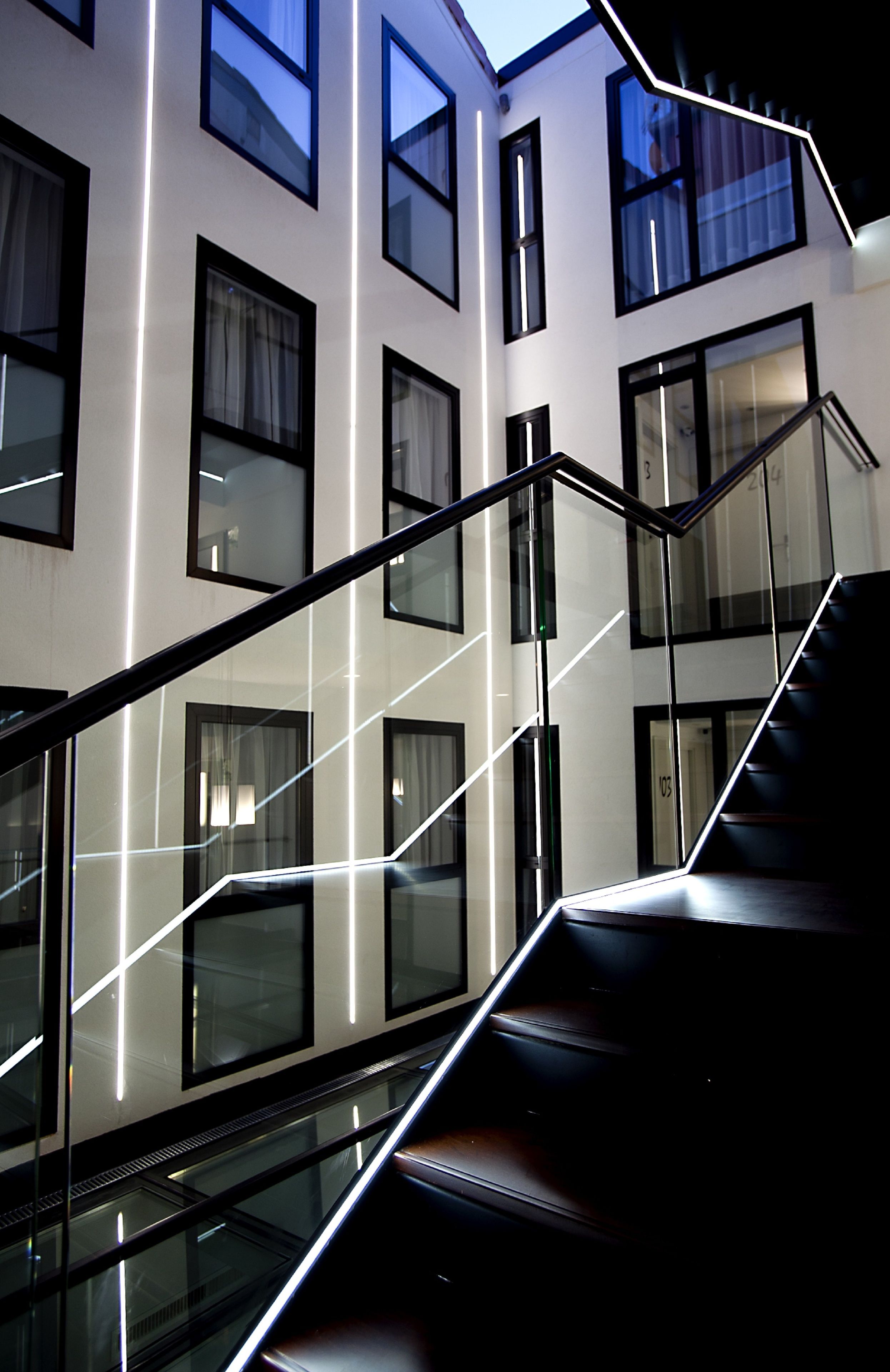A modern building with a glass staircase and multiple windows.