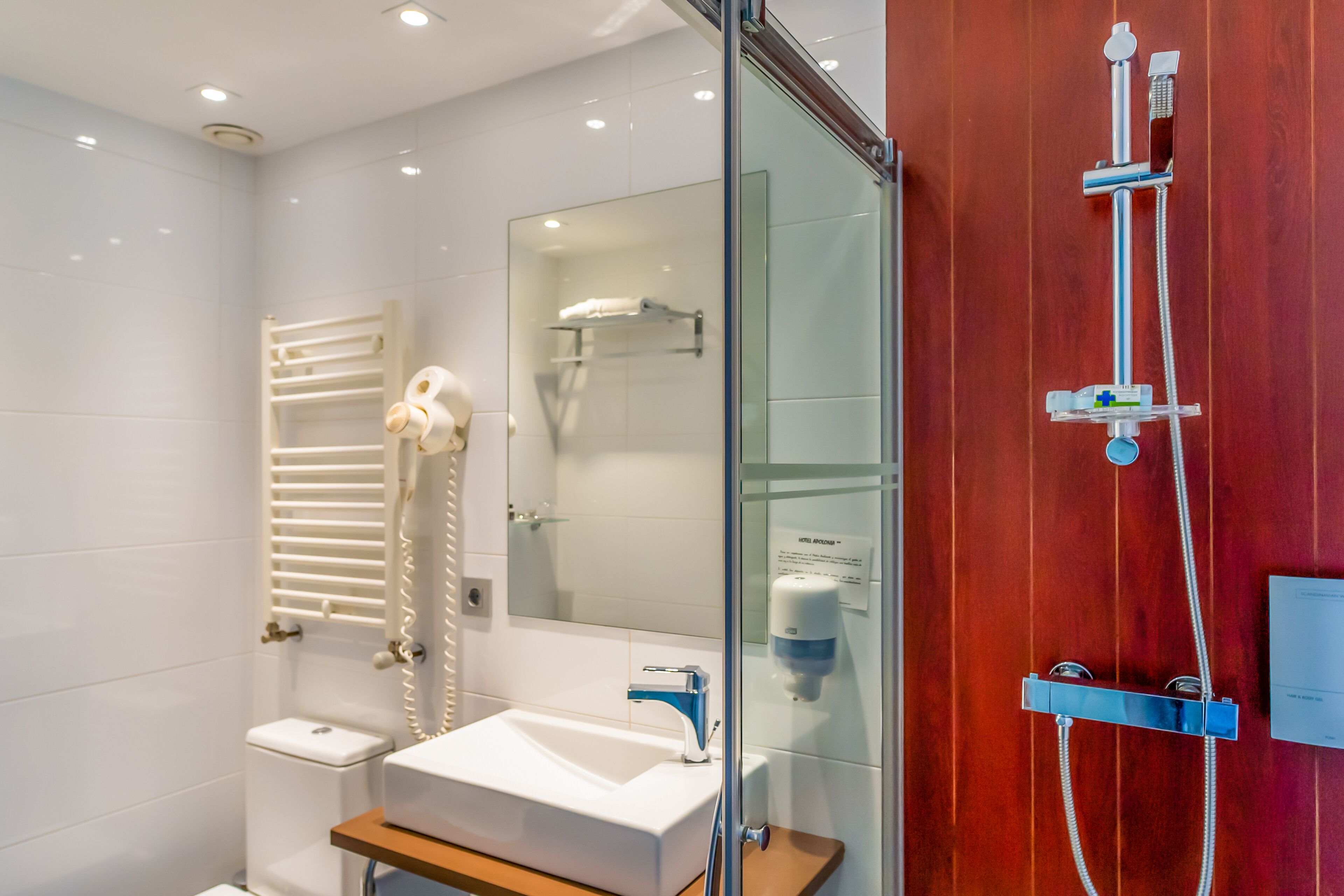 A modern bathroom with a glass-enclosed shower, a white sink, and a wooden vanity.