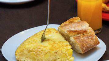 A breakfast plate with a slice of omelette, a glass of orange juice, and a cup of coffee on a table.