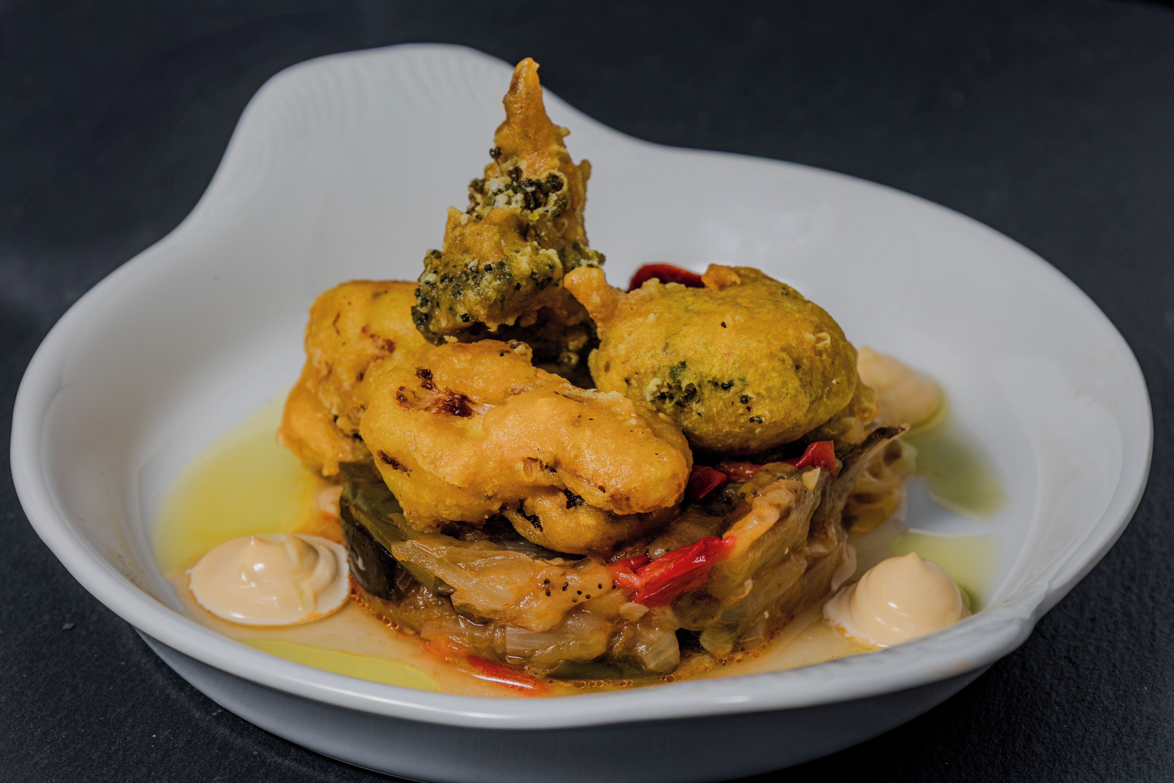 Un bol blanc contenant un plat composé de poulet, de légumes et d’une cuillère de sauce.
