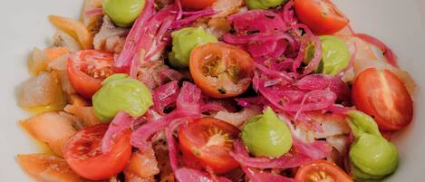 A bowl of salad with tomatoes, onions, and avocado.