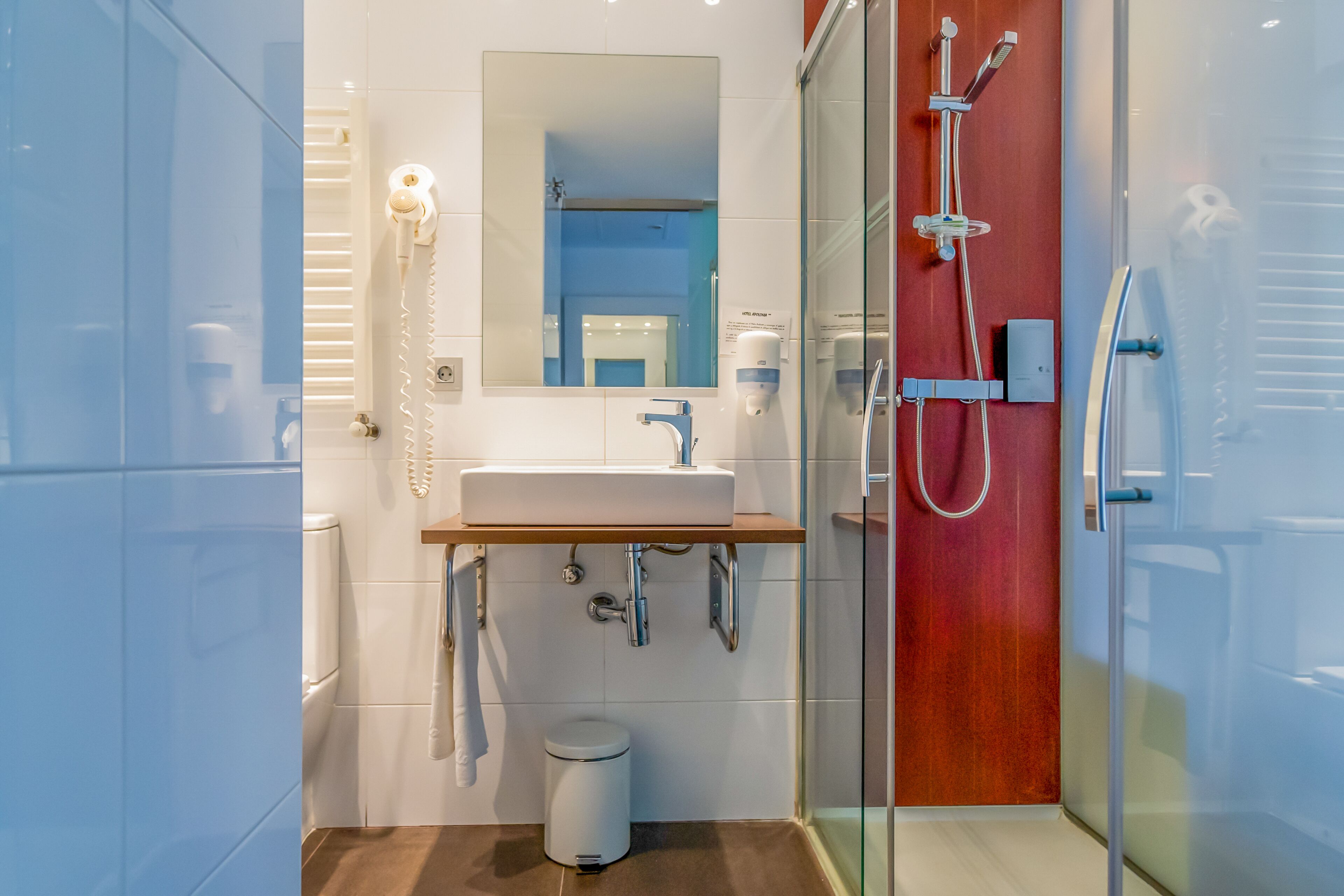 Un baño moderno con cabina de ducha de vidrio, un lavabo blanco y un espejo encima.