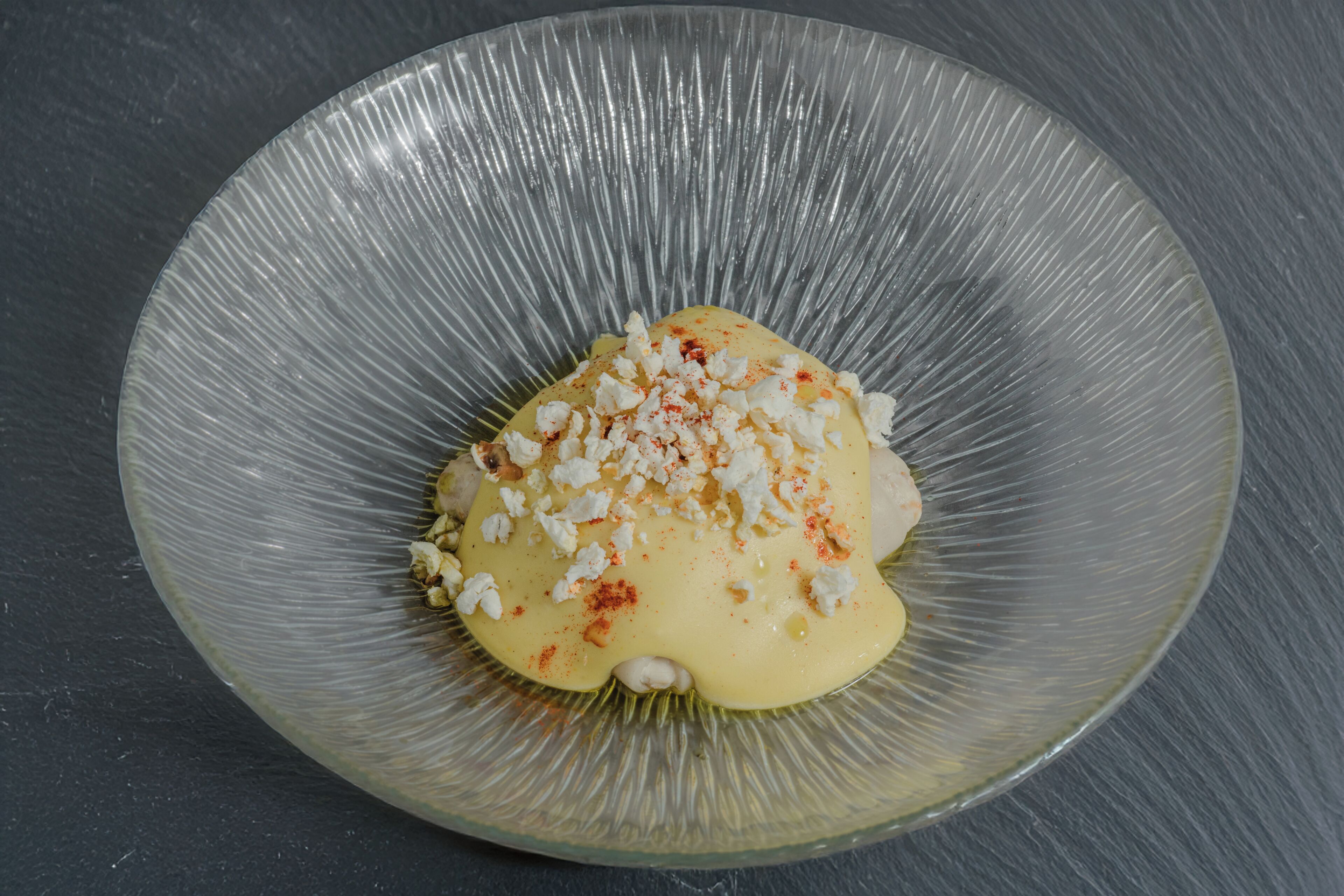 A clear glass bowl with a dessert on a dark surface.