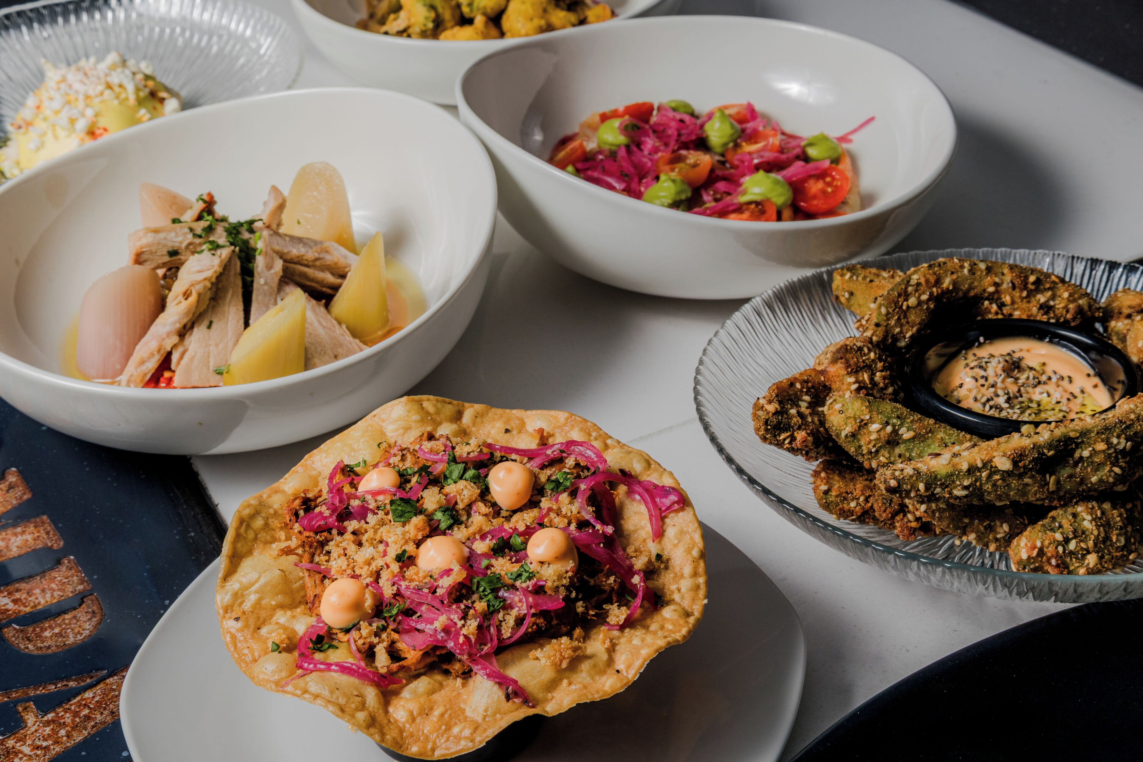 A variety of dishes including a bowl of meat and potatoes, a salad with vegetables, and a plate with bread and sauce.
