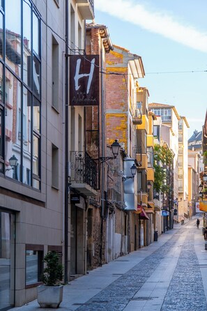 Una calle adoquinada flanqueada por edificios, incluyendo un hotel con un letrero visible.