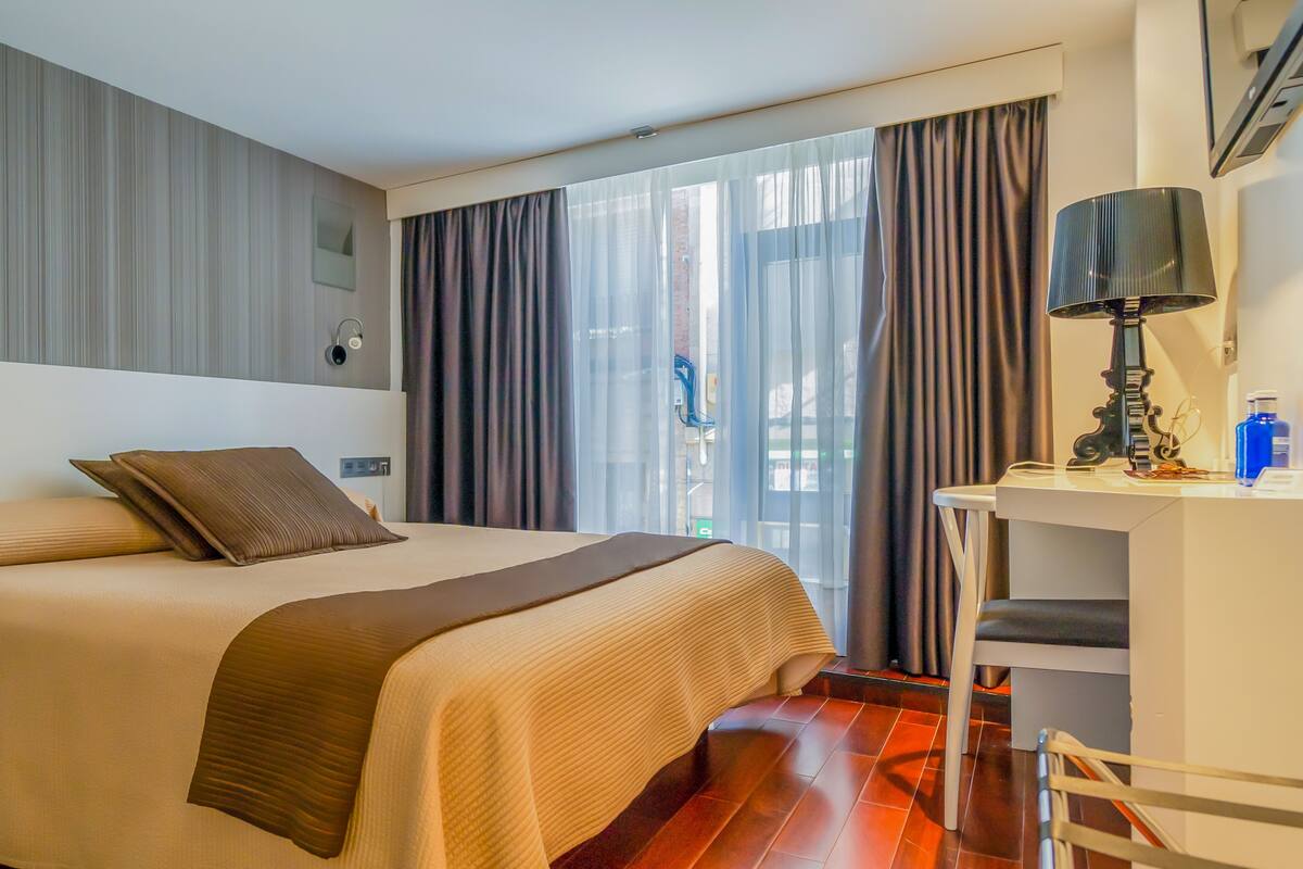 A hotel room with a large bed, a desk, and a chair.