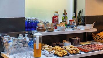 Una mesa de buffet con diversos alimentos, bebidas y salsas.