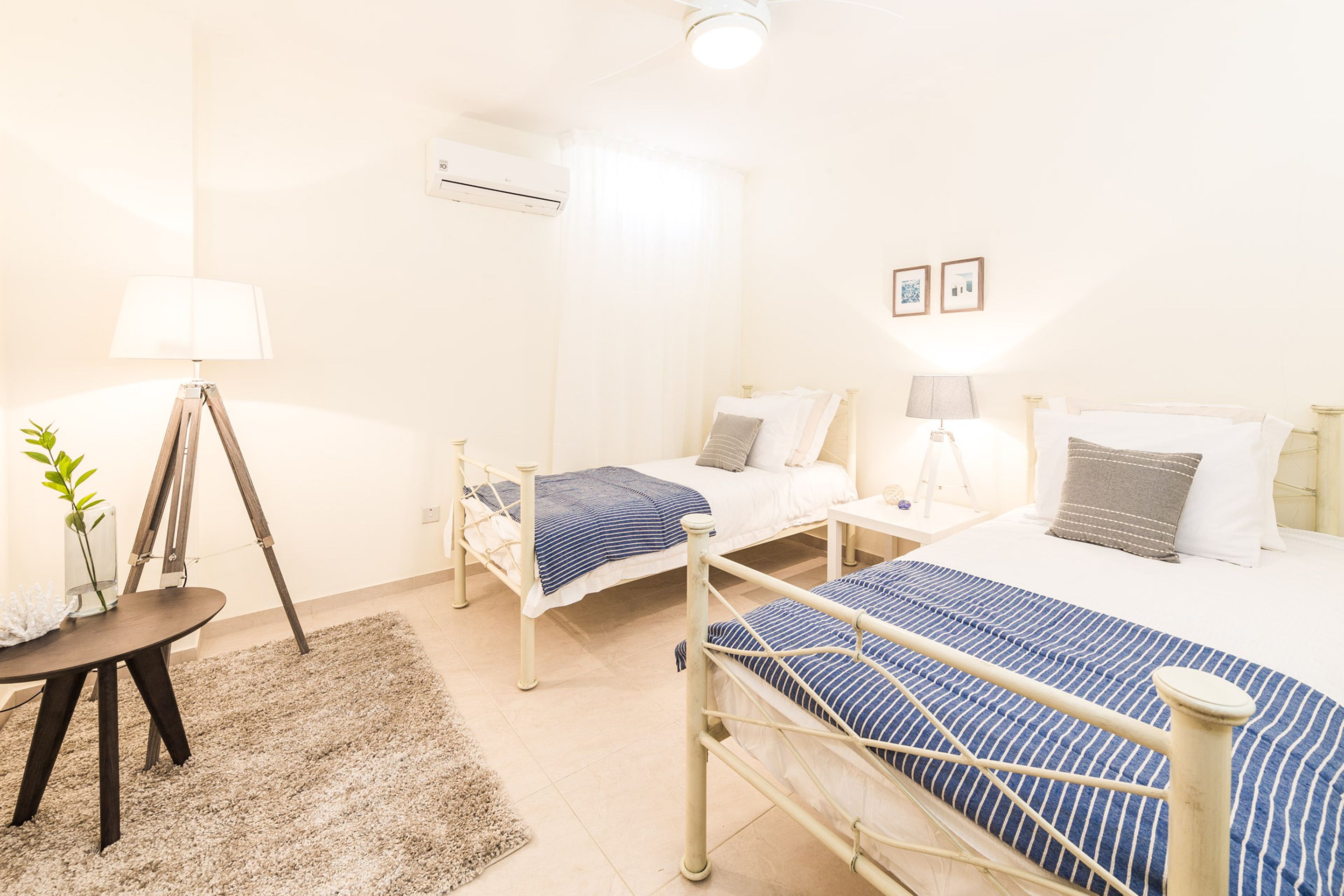 Une chambre d’hôtel avec deux lits, un bureau, une lampe et une petite plante.