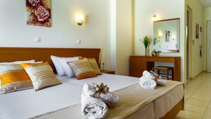 A hotel room with a large bed, two bedside tables, a dresser, a mirror, and a painting on the wall. - Tsambikos Apts (Rhodes)