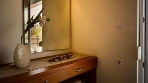 A bathroom with a wooden vanity, a large mirror, and a vase with flowers. - Tsambikos Apts (Rhodes)
