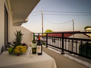 A balcony with a table set for two, featuring a bottle of white wine, a glass, a pineapple, and a bowl of bananas. - Tsambikos Apts (Rhodes)