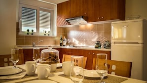 A modern kitchen with wooden cabinets, a built-in oven, and a window with blinds. - Tsambikos Apts (Rhodes)