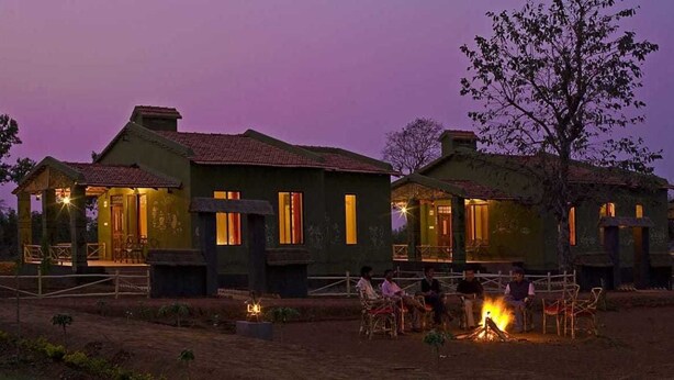 Una hilera de edificios de estilo rústico con iluminación cálida, un pozo de fuego y asientos al aire libre.