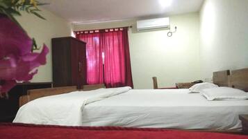 Un dormitorio con cama, armario, mesita de noche y ventana con cortinas rojas.