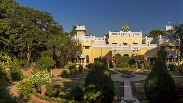 Un edificio grande y amarillo con un patio central, rodeado de follaje y árboles.