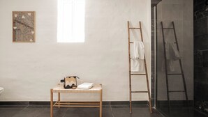 Een badkamer met een houten bankje, een ladder en een douchegedeelte.