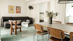 Een moderne woonkamer met een bank, een eettafel met stoelen, een salontafel en een grote spiegel.