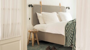Een slaapkamer met een bed, een nachtkastje, een lamp en een paar schoenen op de vloer.