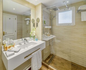 Un baño moderno con un espejo grande, dos lavamanos, una ducha y una ventana.
