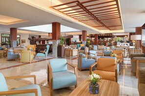 Un amplio vestíbulo de hotel con varias zonas de estar, un bar y una chimenea.