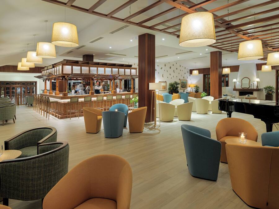 A spacious lobby with a bar area, seating arrangements, and a grand piano.