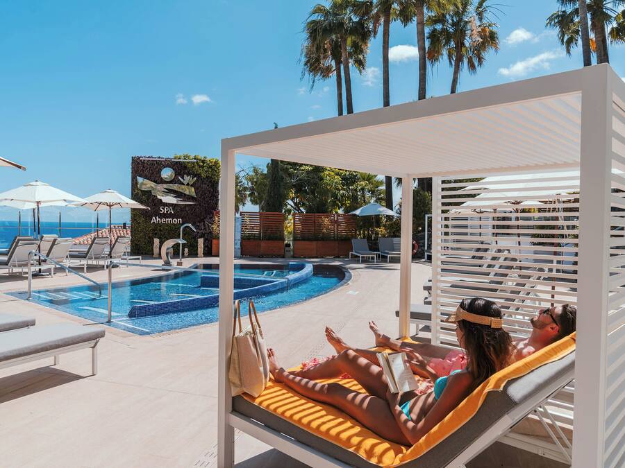 Een zwembadgedeelte met ligbedden, parasols en een bord dat een spa aangeeft.