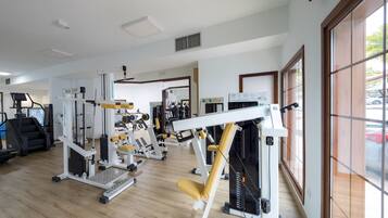 Une salle de sport équipée de divers appareils d’exercice, d’un tapis de course et d’un miroir.