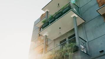 A multi-story building with a balcony on the second floor, featuring a small garden area.
