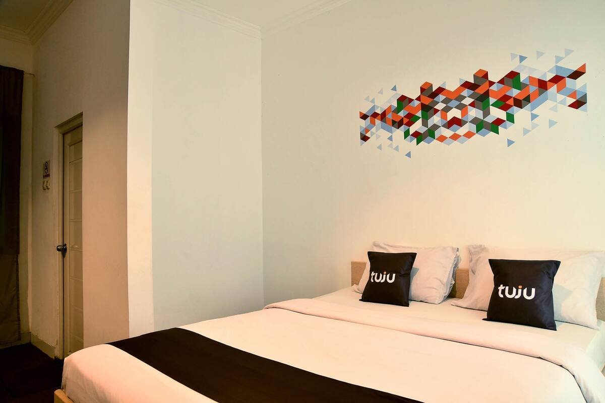 A hotel room with a bed, a wall art piece, and a door.