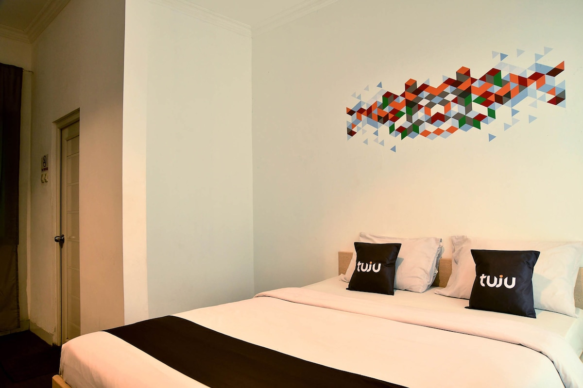 A hotel room with a bed, a wall art piece, and a door.