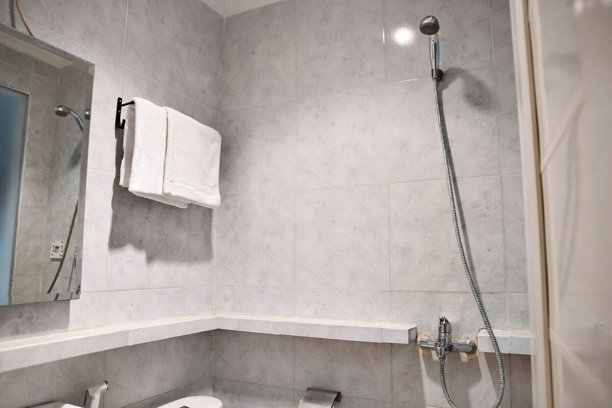 A bathroom with a shower, a towel rack, and a mirror.