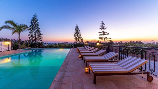 A rooftop pool area with lounge chairs and a sunset view. - Villa Mojito (Pegeia)