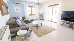 A modern living room with a sofa, a coffee table, and a TV. - Villa Mojito (Pegeia)