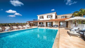 Una casa de dues plantes amb piscina, mobiliari exterior i vistes al mar.