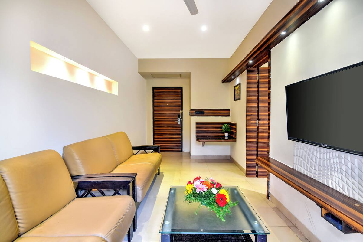 A modern living room with a sofa, coffee table with flowers, a TV, and wooden decor.