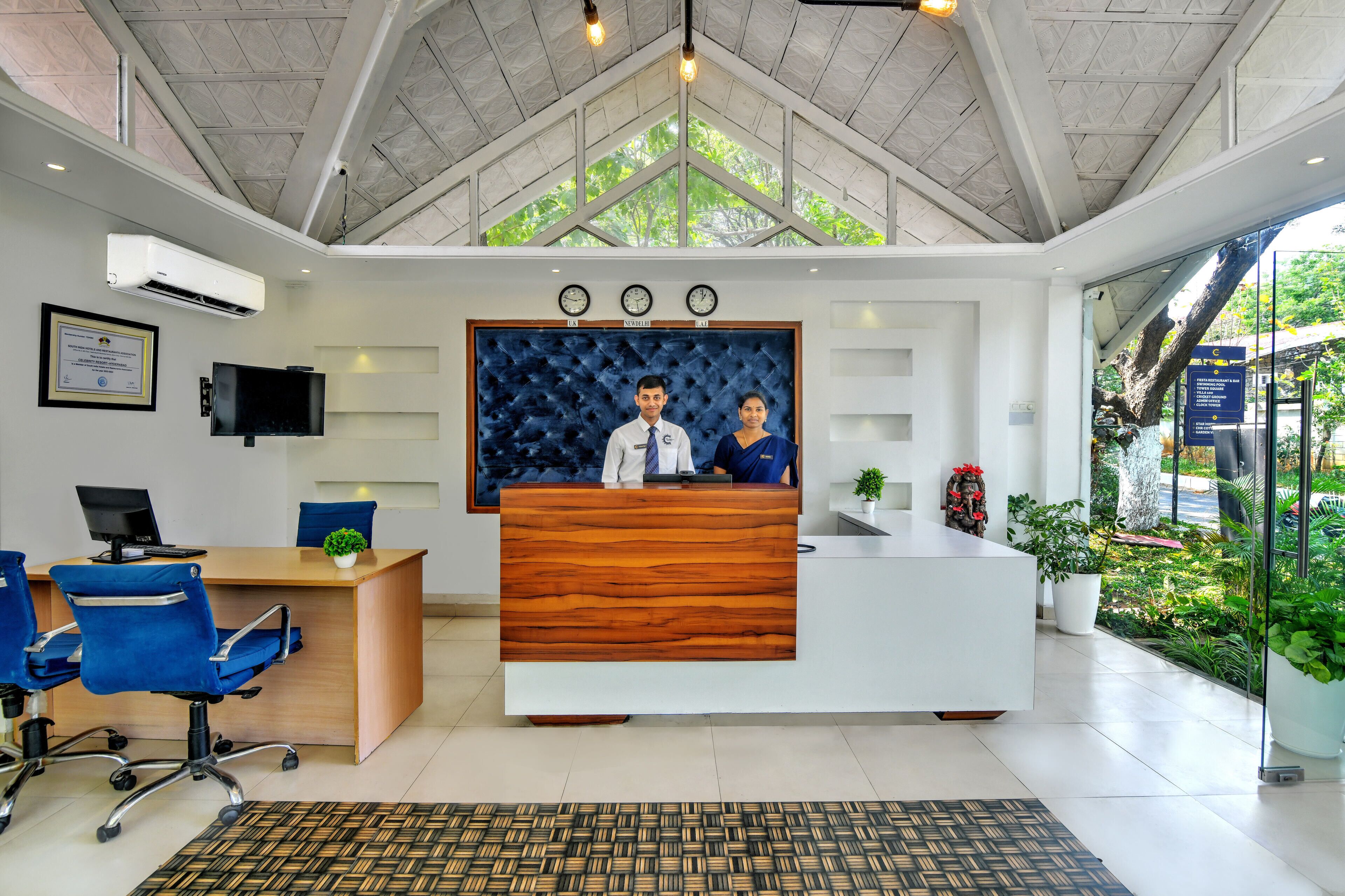 A reception desk with a wooden finish, a television mounted on the wall, and a framed certificate.