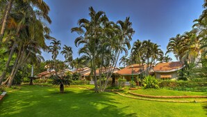 Un complexe hôtelier tropical doté d’une végétation luxuriante, de palmiers et d’une pelouse bien entretenue.