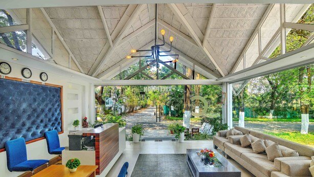 Un intérieur moderne avec un plafond haut, un comptoir d’accueil, un espace salon et une vue sur l’extérieur.