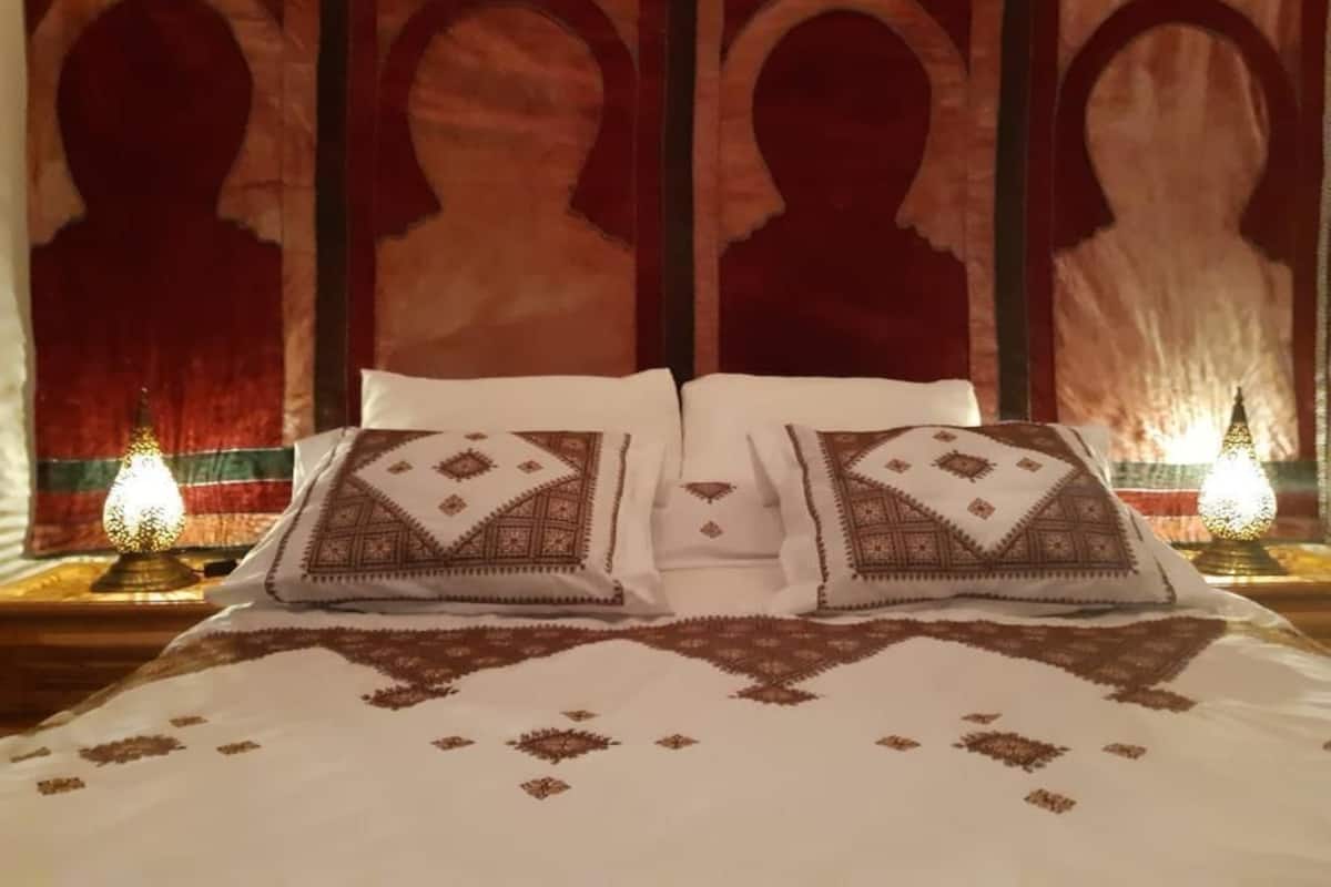 A bed with patterned pillows, a headboard with silhouette designs, and two bedside lamps.